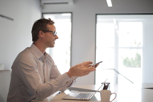 a-person-holding-a-phone-at-their-desk